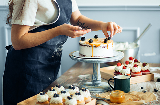 Mujer repostera haciendo una tarta en pastelería